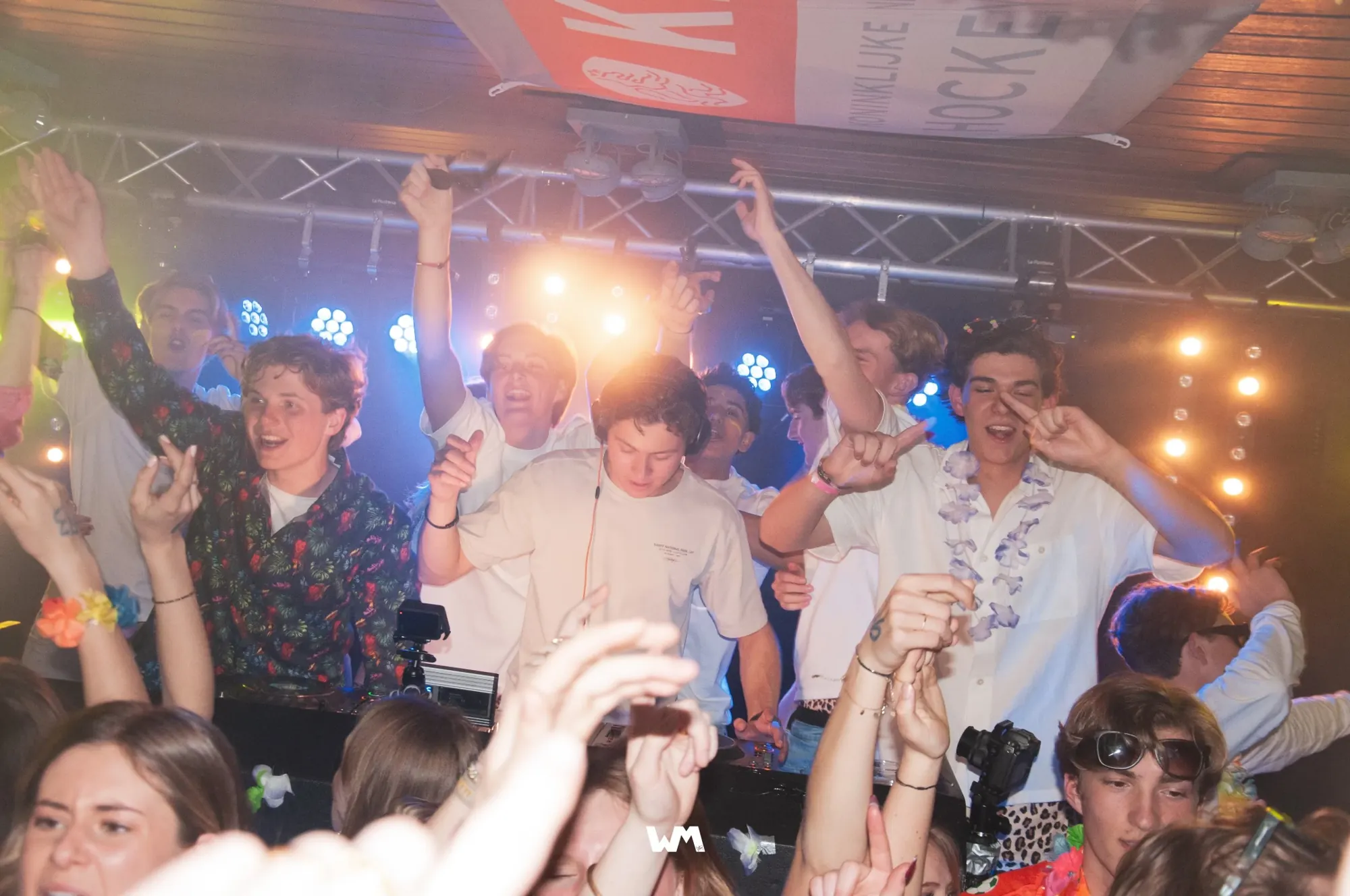 Volle dansvloer rond de DJ booth onder de lichtbrug